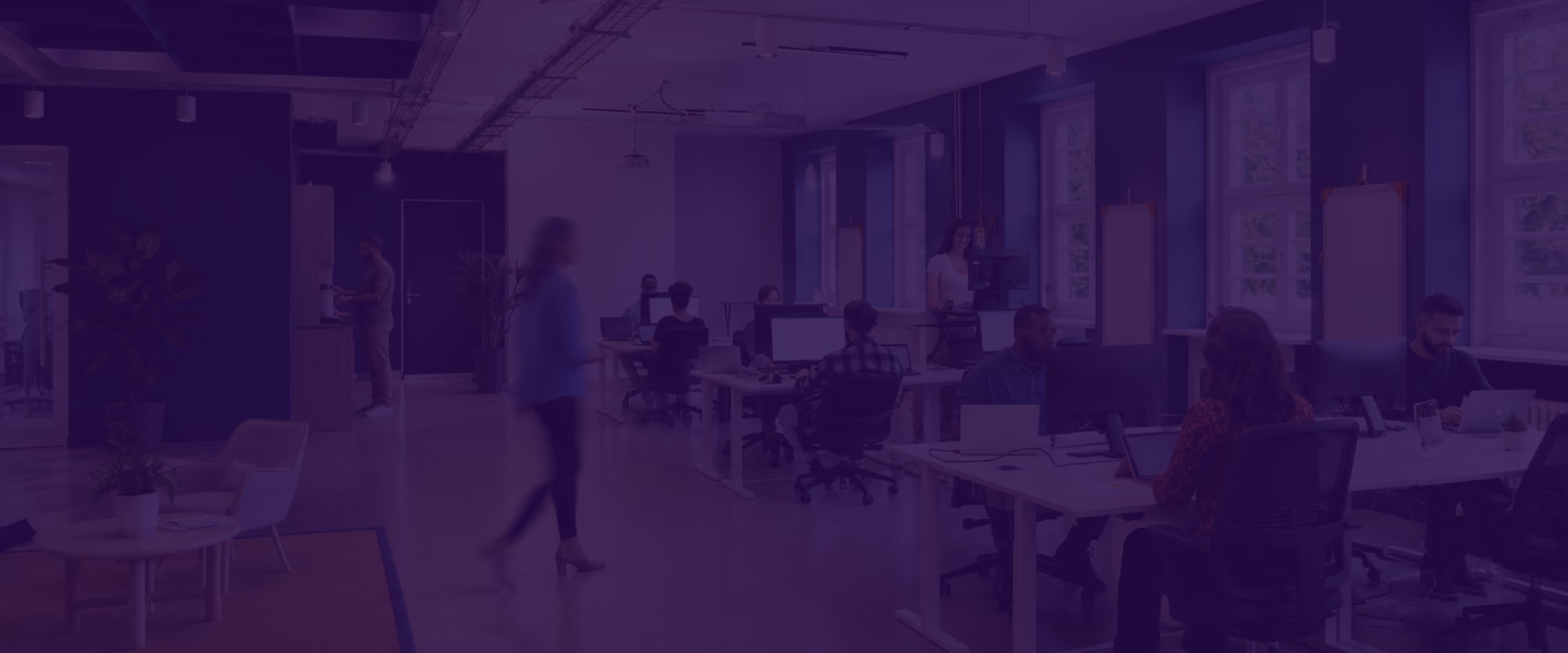 Modern workspace with people working at desks and walking by