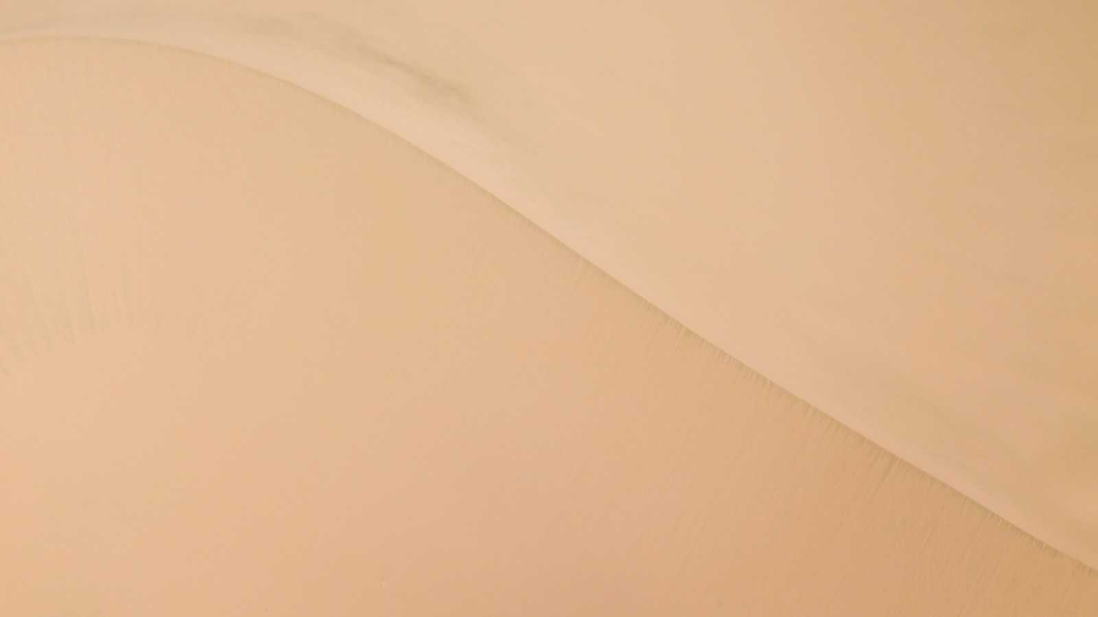 Smooth peach-toned surface with a soft diagonal curve, abstract