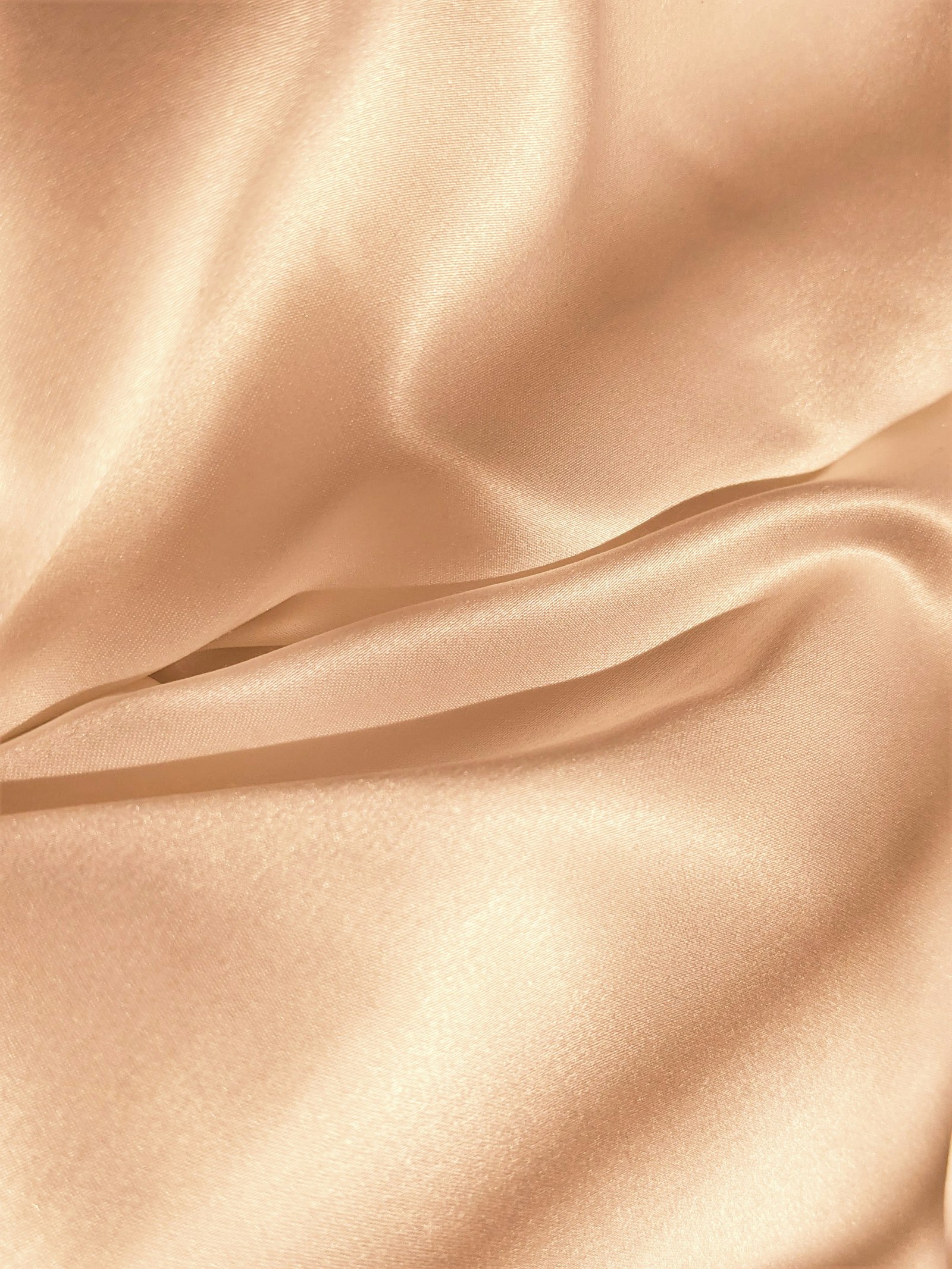 Soft rose-toned silk fabric with gentle folds, abstract