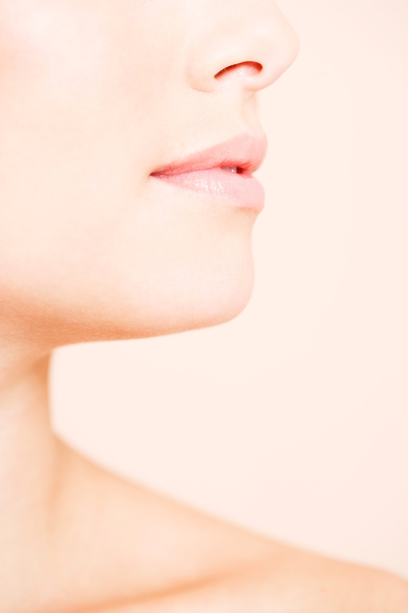 Close profile of a chin and jaw against a pale pink background