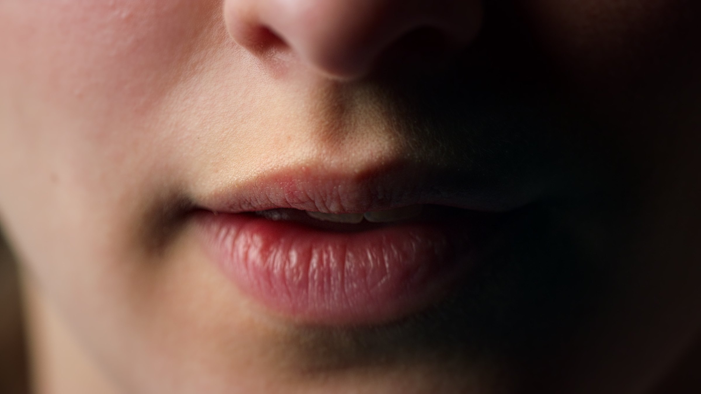 Close-up of natural lips and chin in soft directional shadow