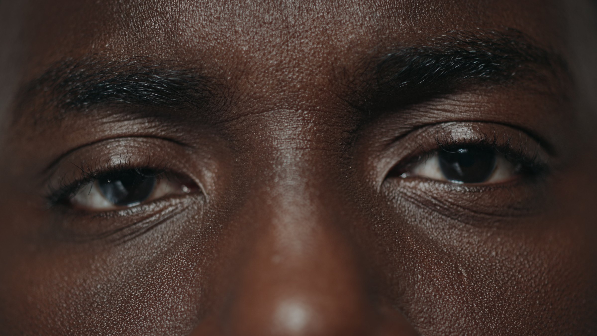 Macro close-up of a brow and eyes on deep brown skin
