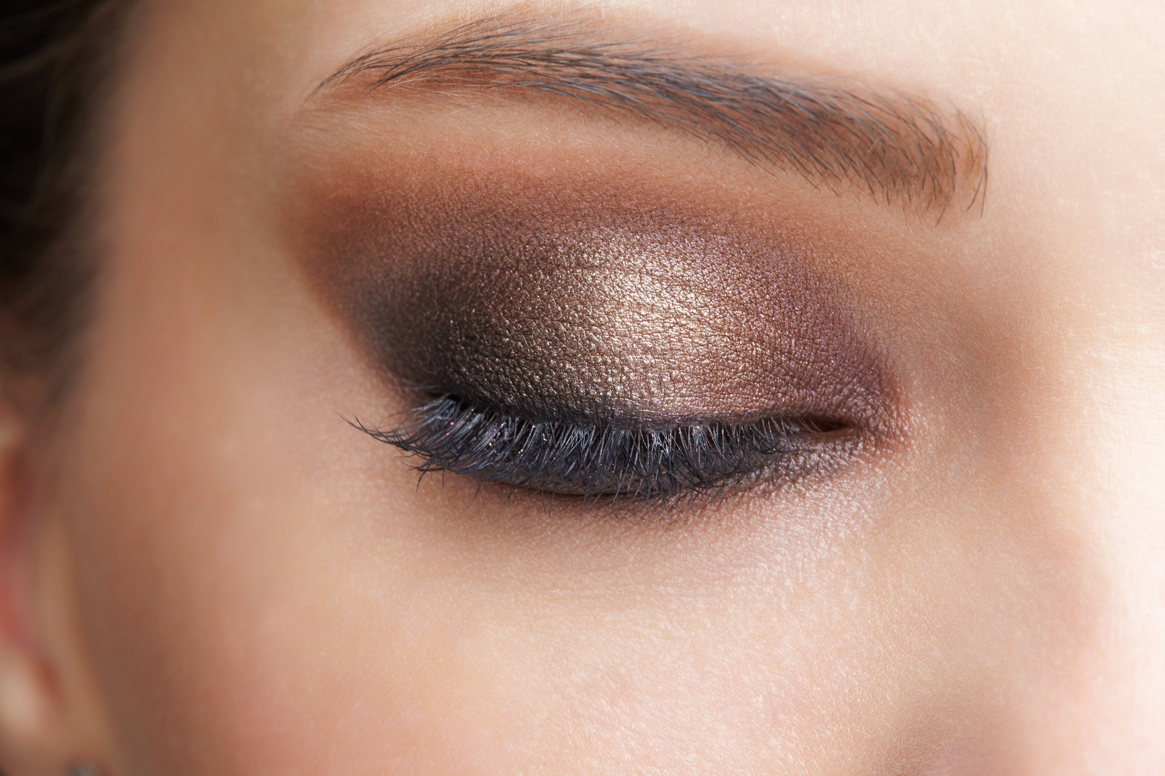 Close-up of a closed eye and brow with bronze eye makeup