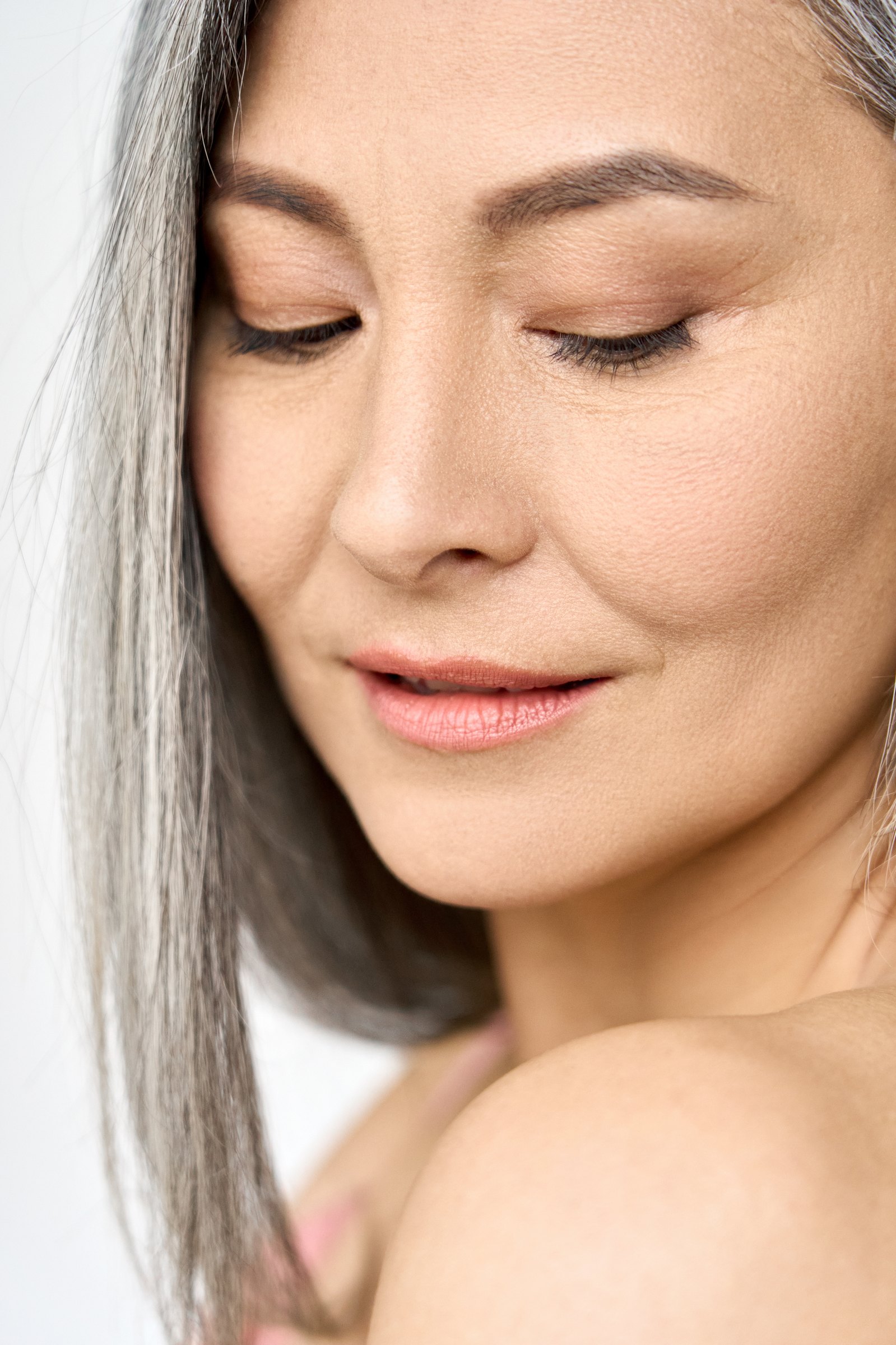 Close portrait of a silver-haired woman with her eyes lowered