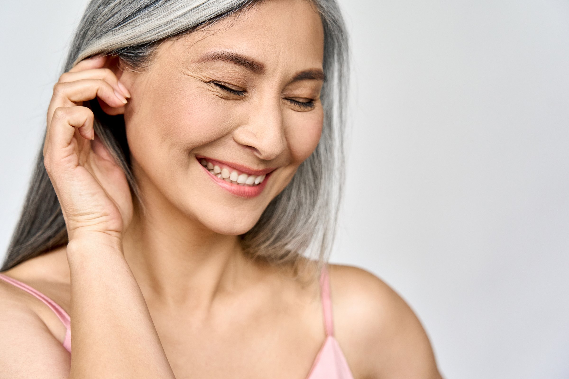 Portrait of a smiling silver-haired woman with her hand beside her face