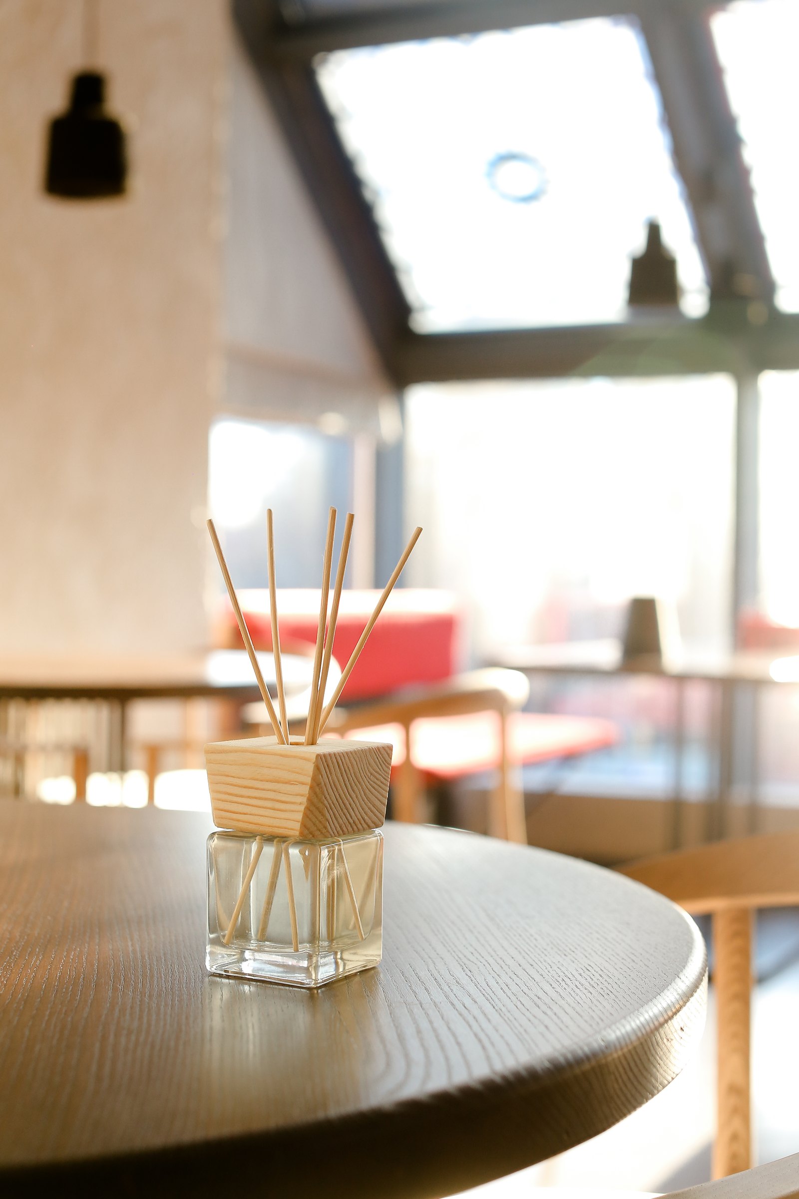 A reed diffuser on a wooden table, warm window light behind
