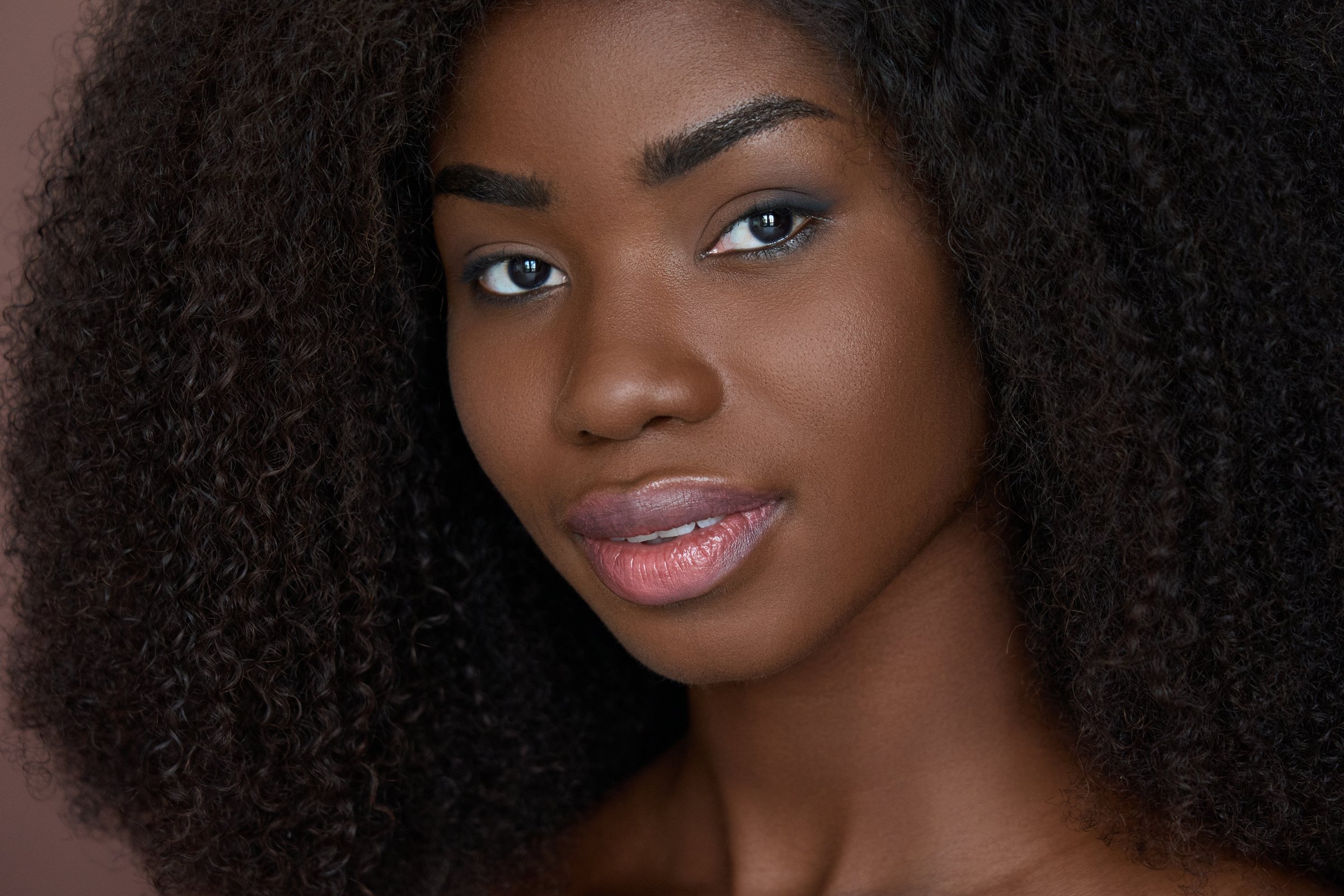 Portrait of a woman looking to camera against a warm brown background