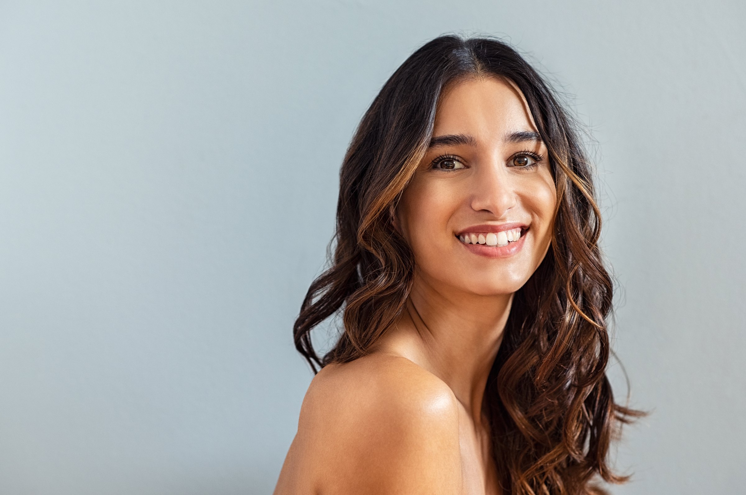 Portrait of a woman with long dark hair against a plain grey background