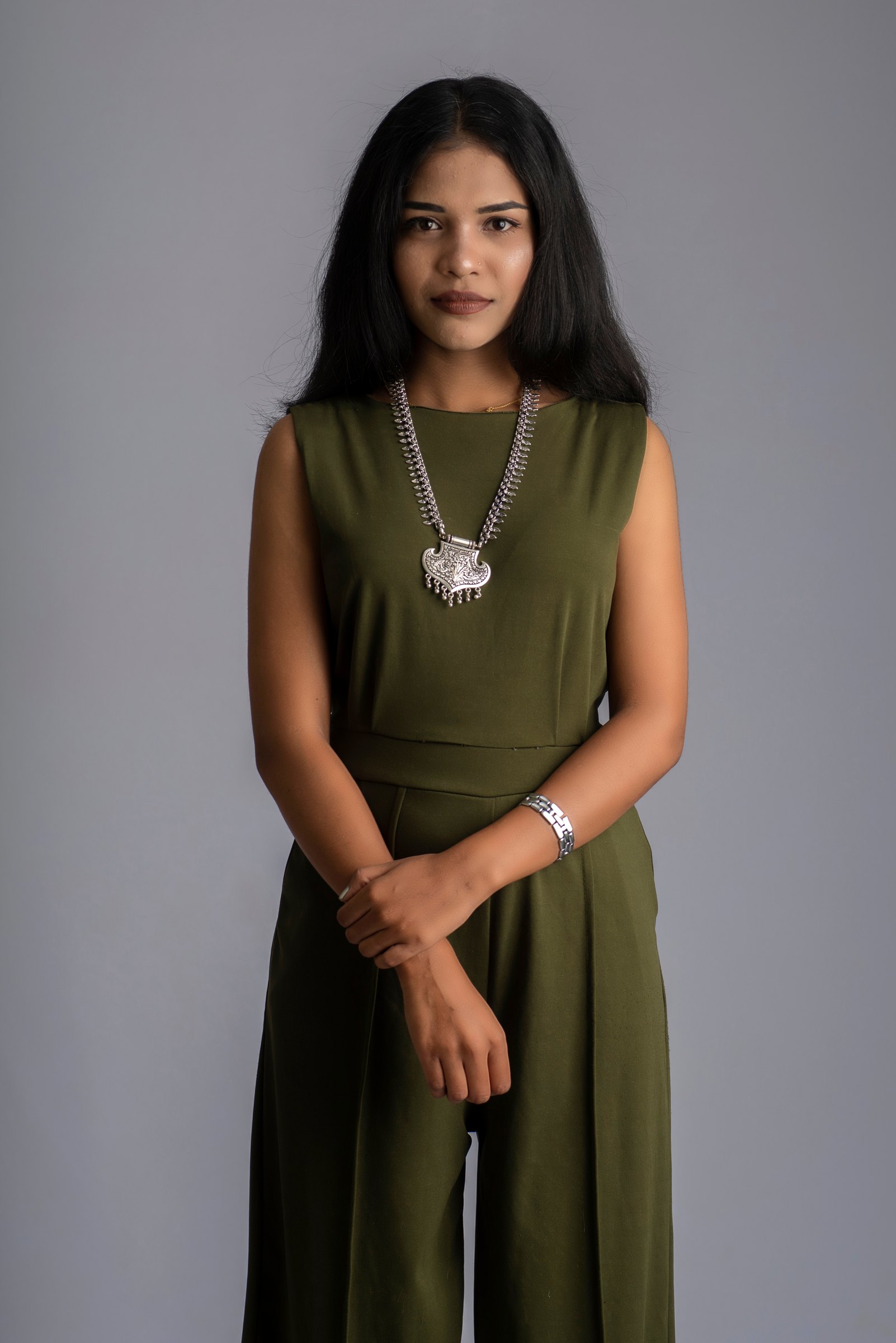 Studio portrait of a woman in an olive dress against grey