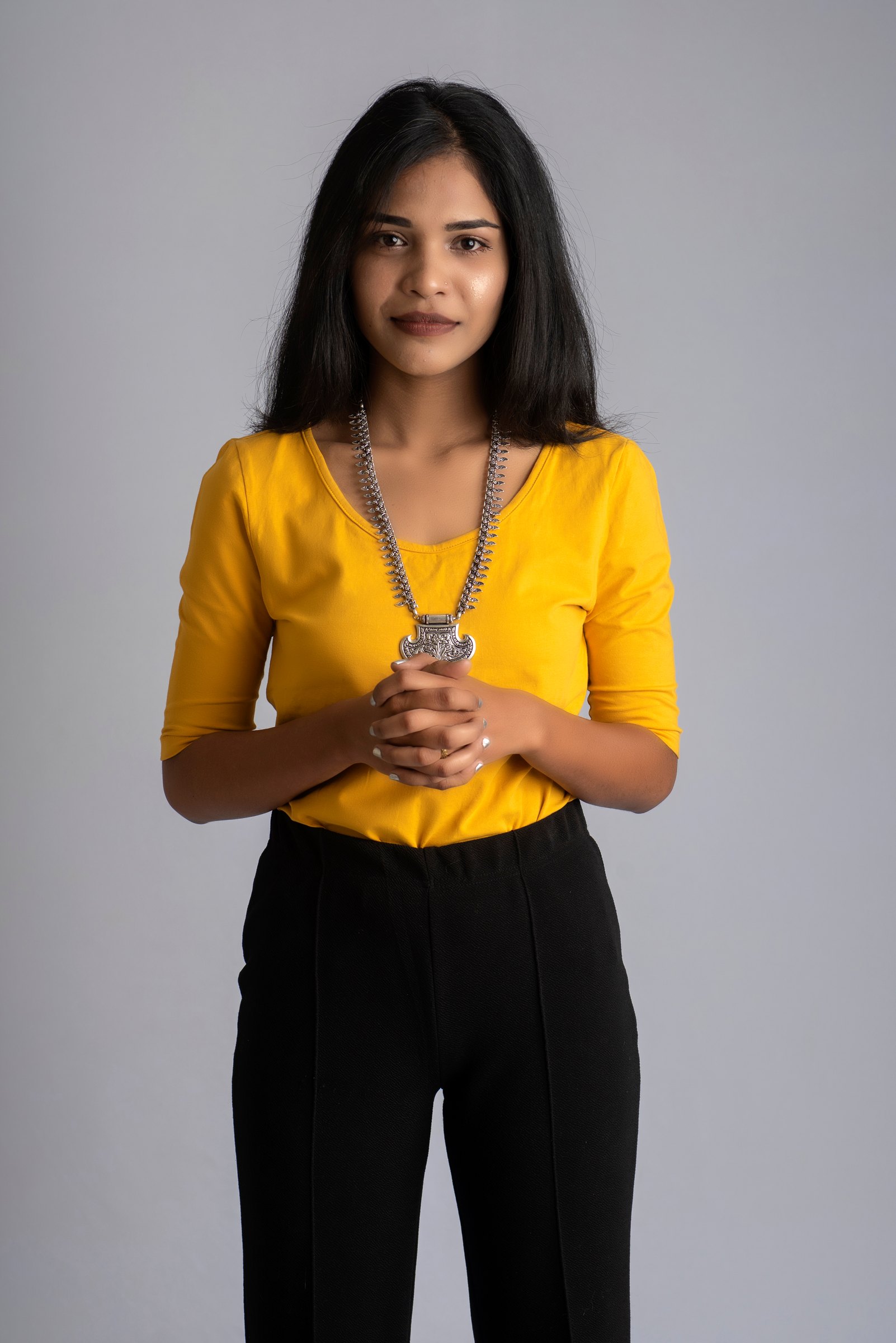 Studio portrait of a woman in a yellow top against grey