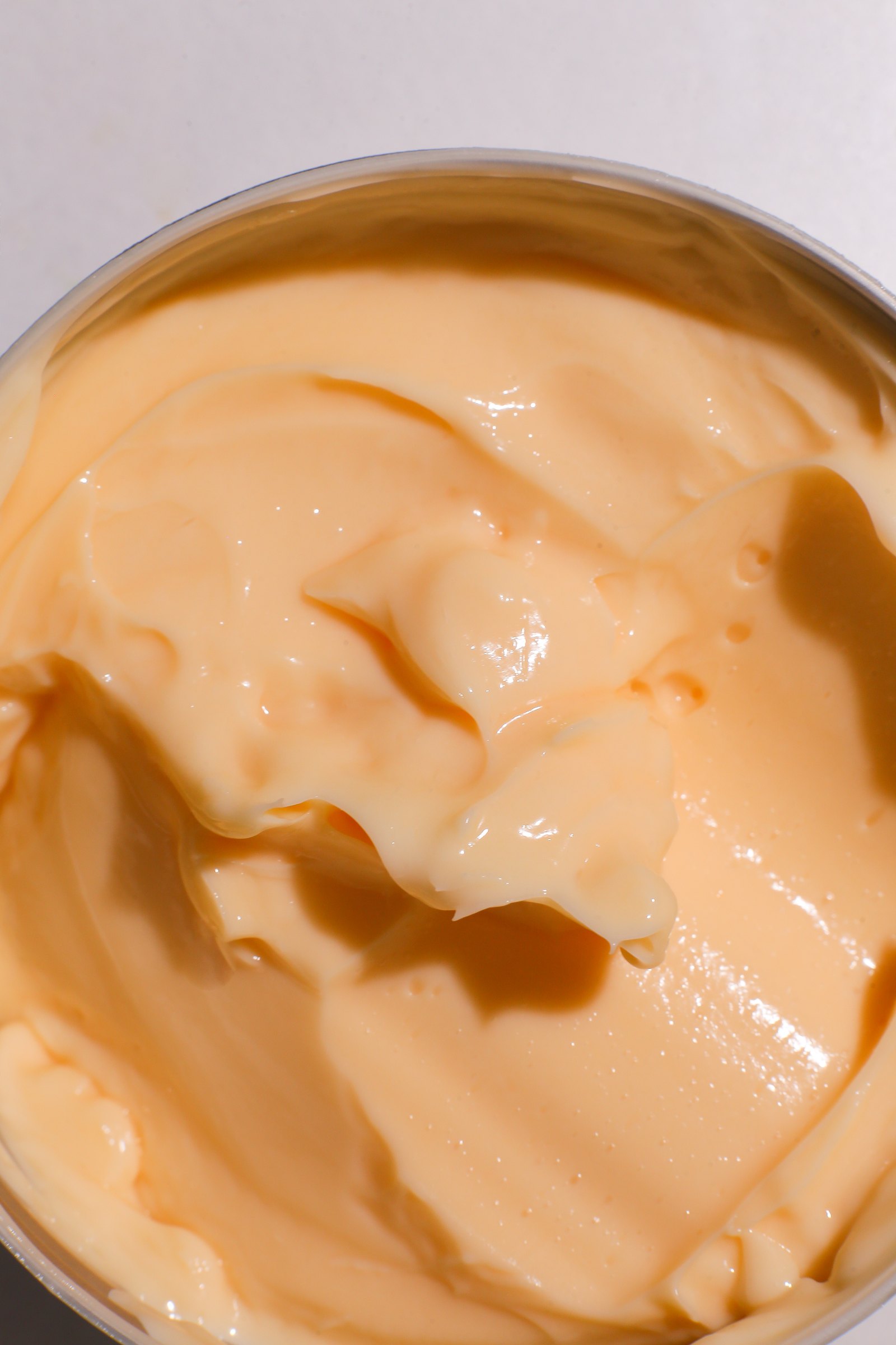 Swirl of pale cream in a shallow jar, warm overhead light