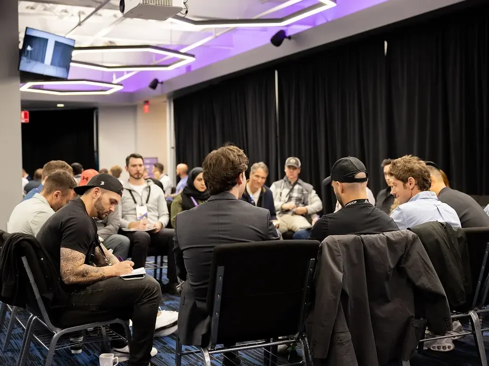 Founders working in small groups at the Acquisition.com workshop