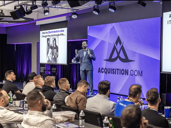 Speaker on stage at the Acquisition.com workshop