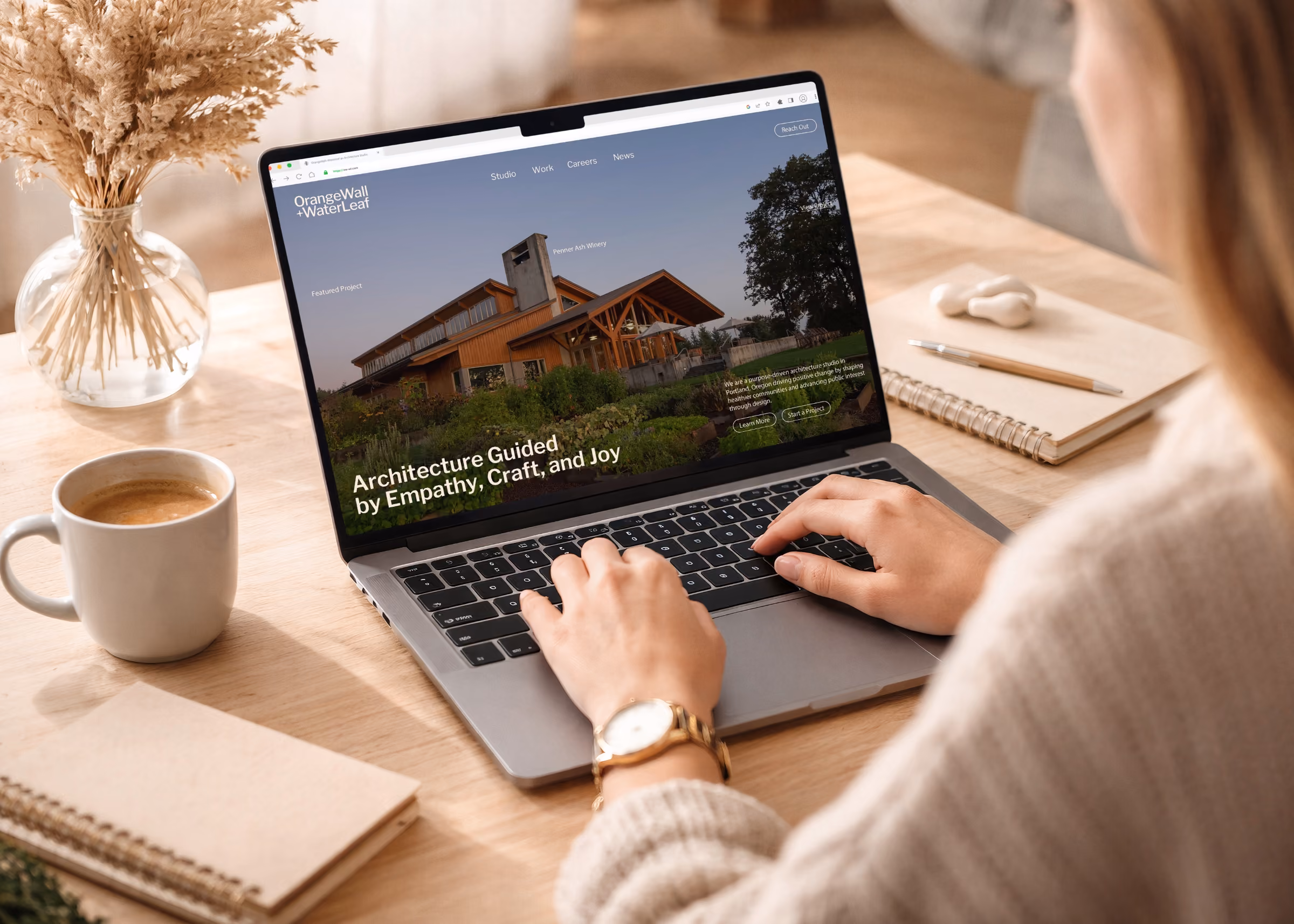 Person typing on a laptop showing OrangeWall+WaterLeaf architecture website.