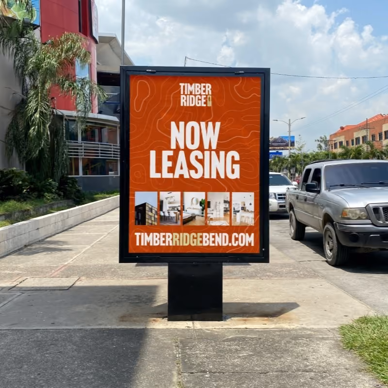 Outdoor advertisement board on a sidewalk showing Timber Ridge leasing information.