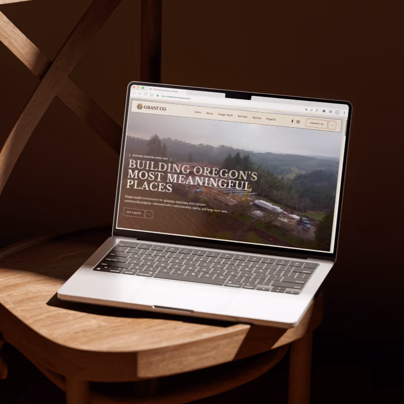 Laptop on a wooden chair displaying a website for The Grant Company