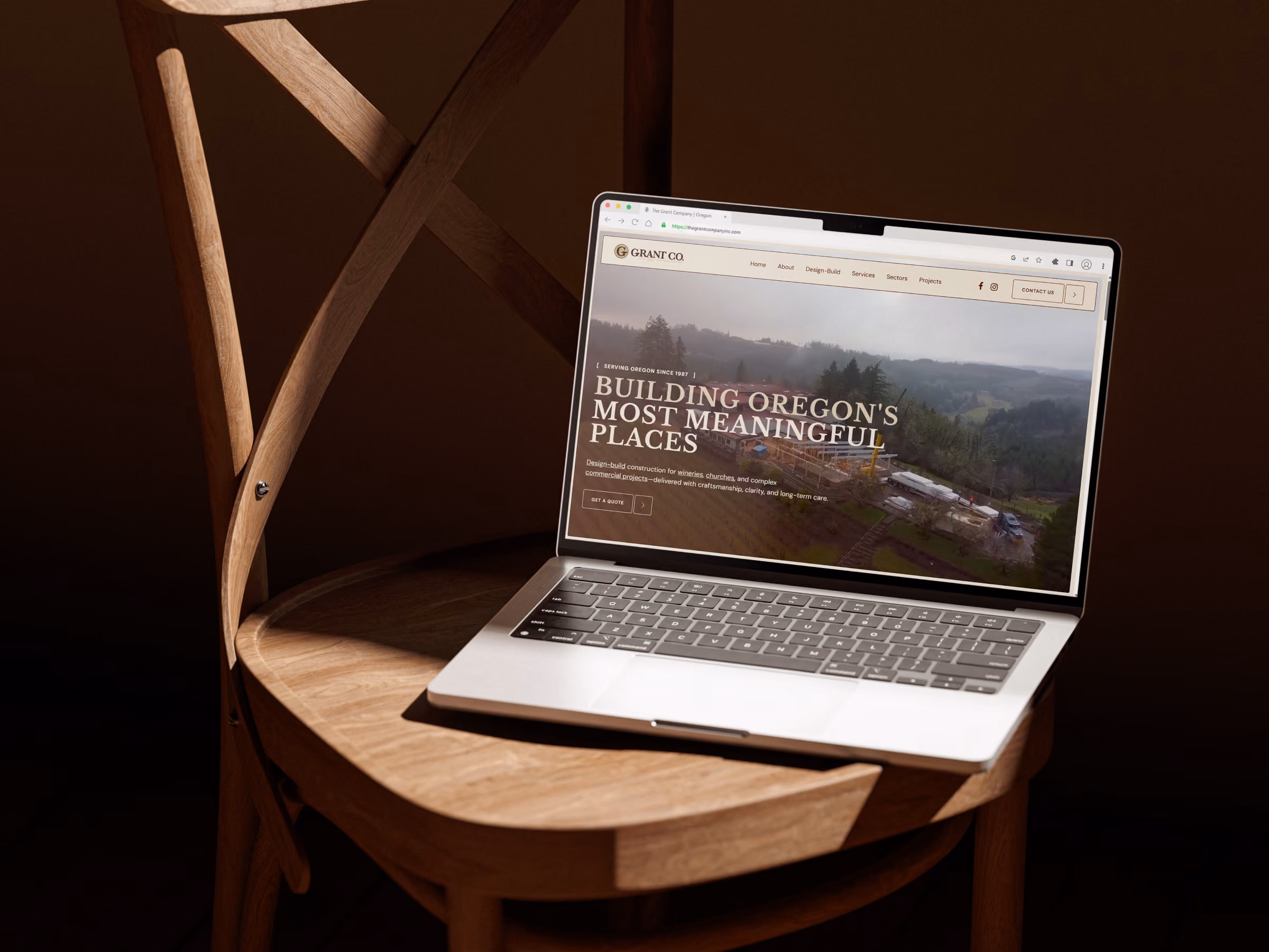 Open laptop on a wooden chair displaying The Grant Company website homepage.