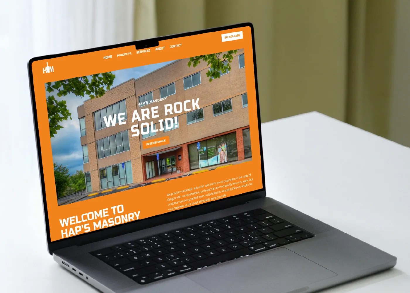 Image of a laptop open to a construction website with bright orange background.