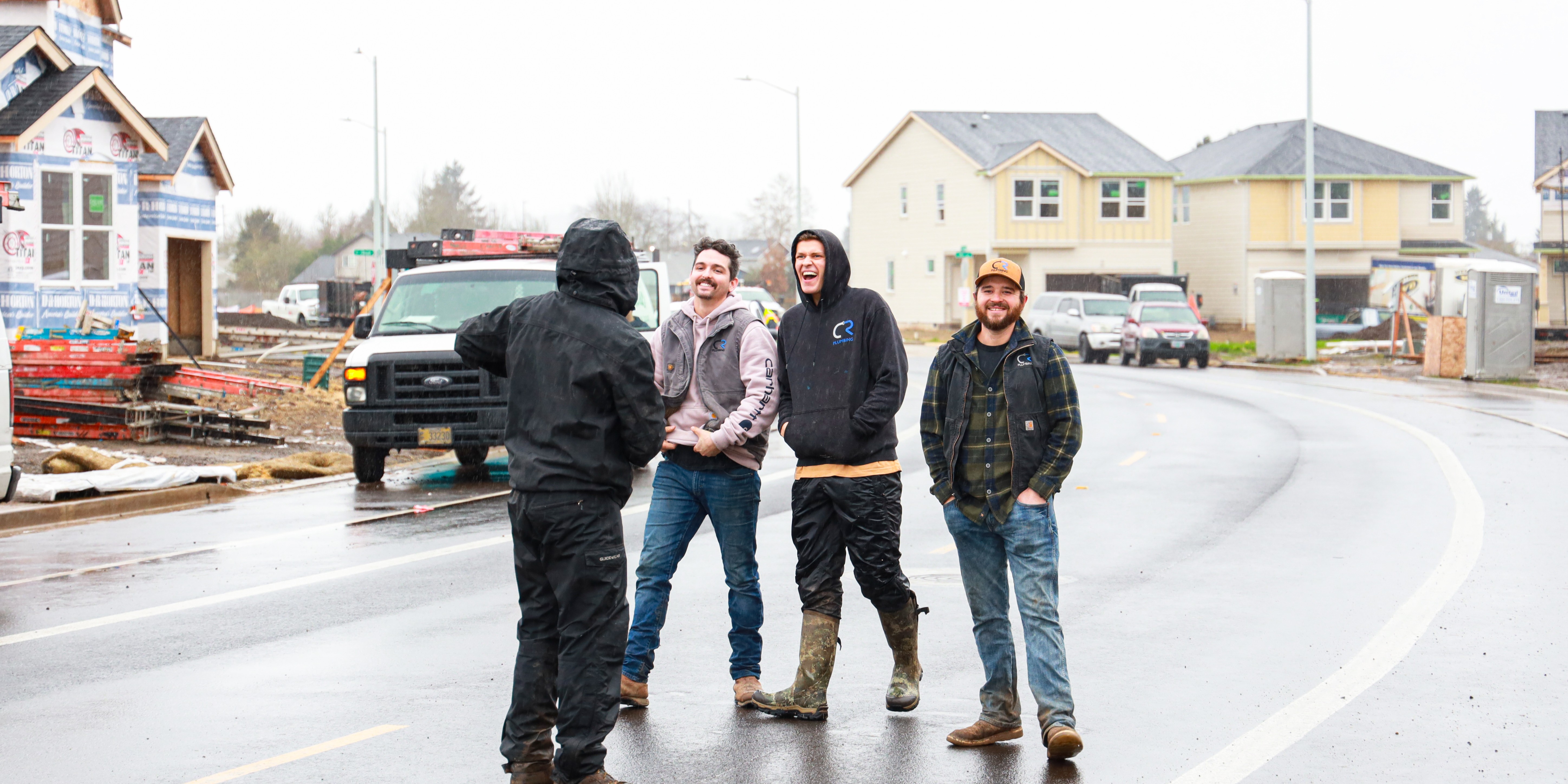 Group of 4 construction workers walking in the street with construction happening around them.
