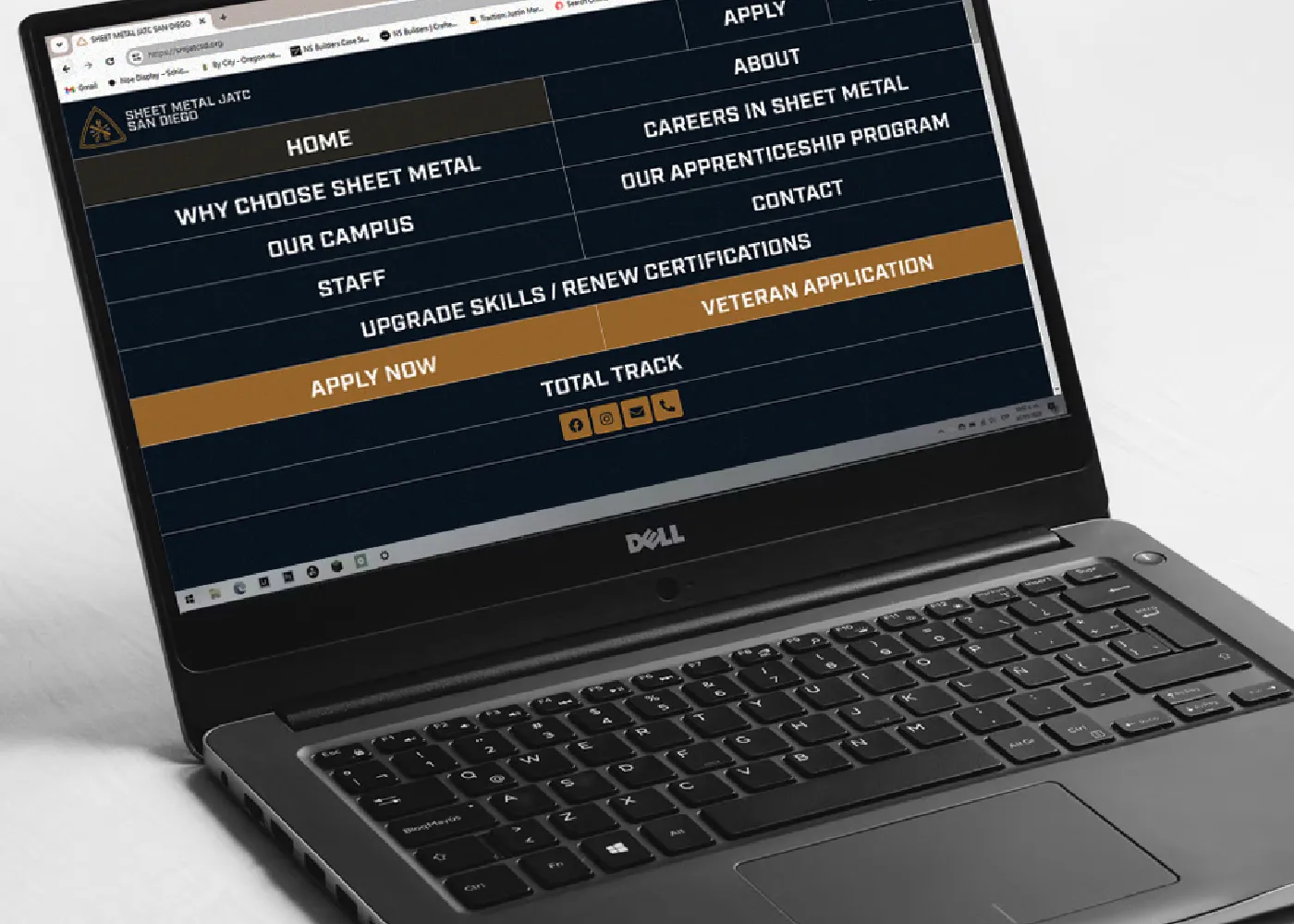 Laptop open to website menu screen. Dark blue with gold highlights.