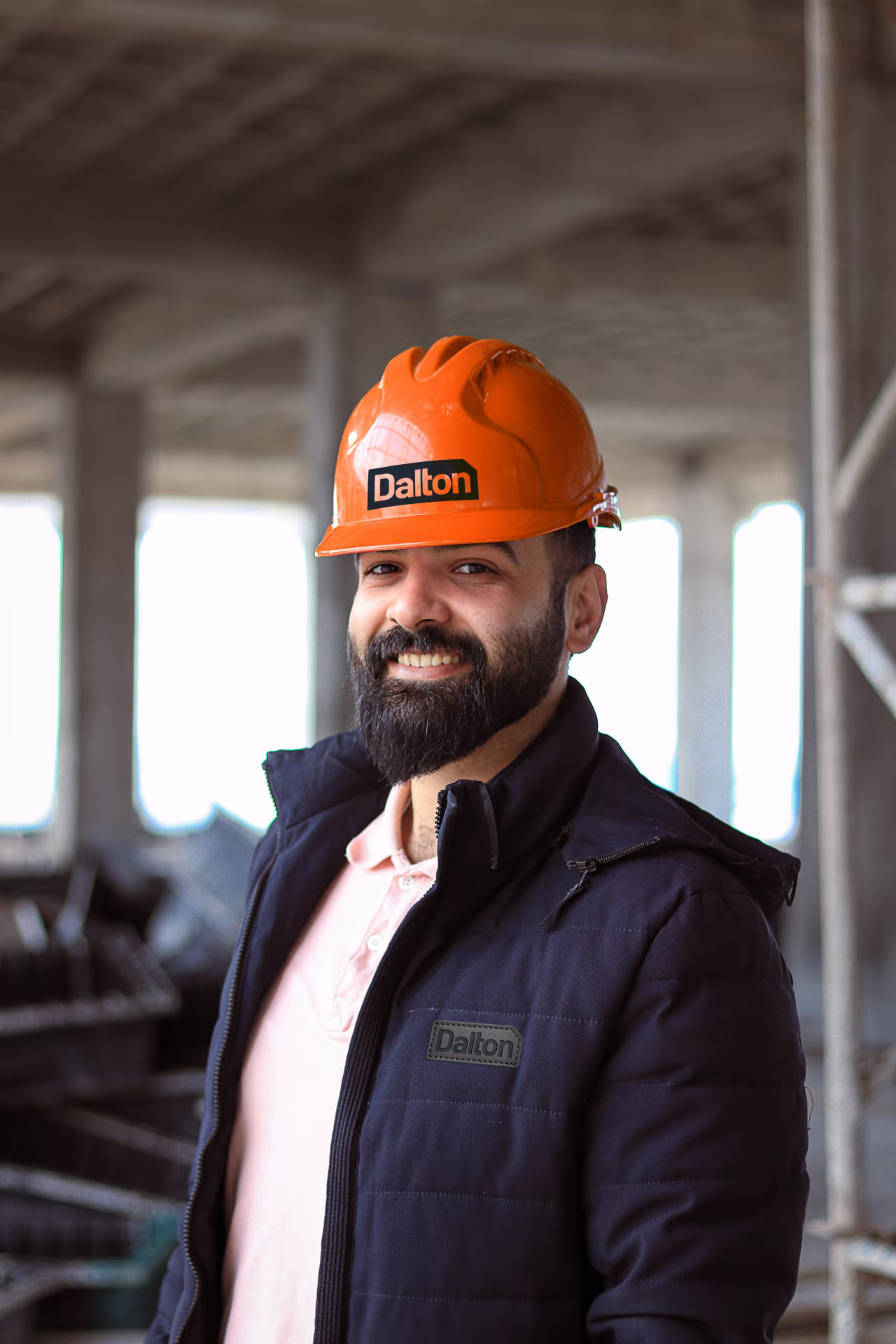 Dalton Engineers employee on project site wearing bright orange hardhat with Dalton Engineers logo on the front.