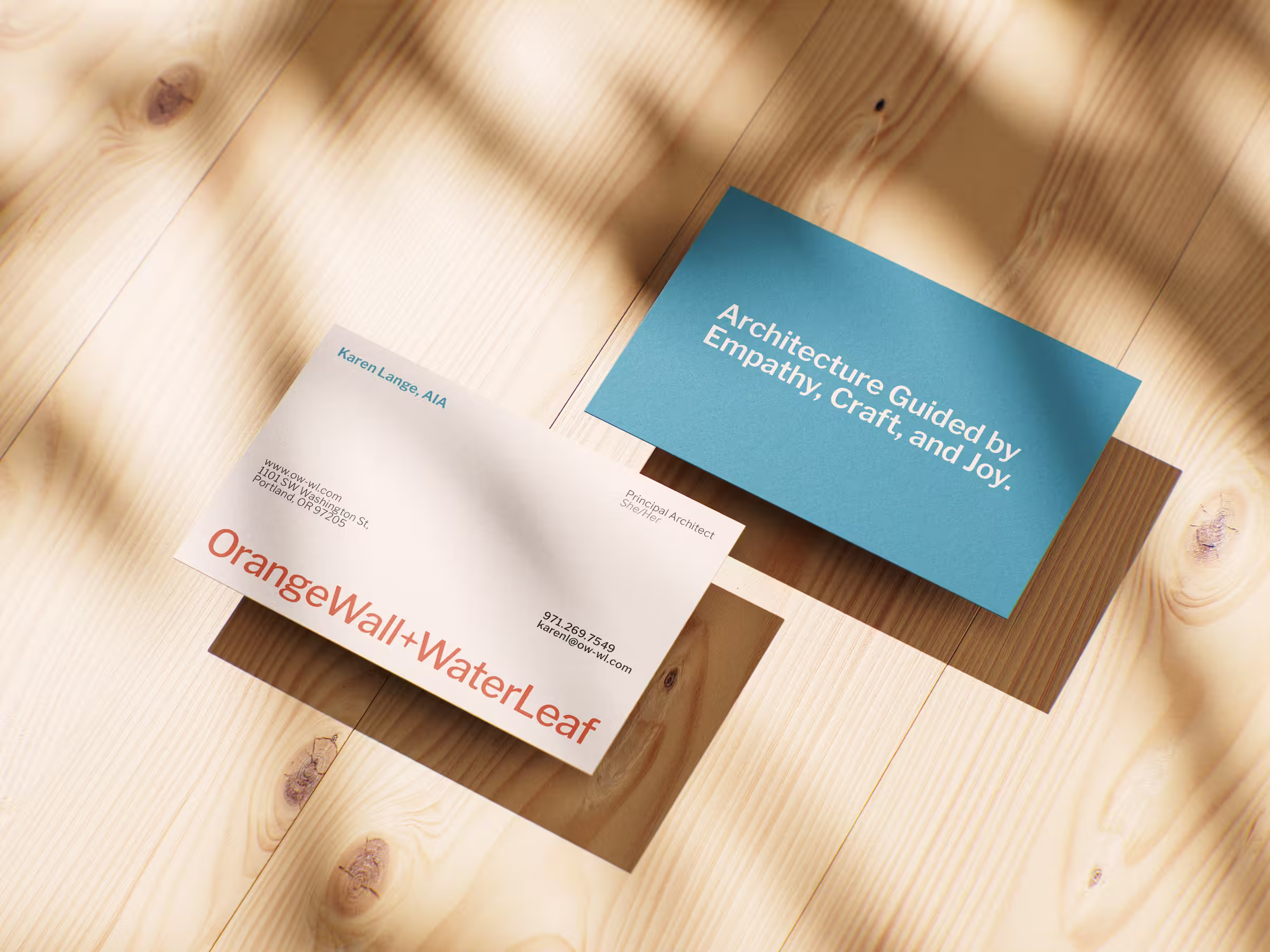 OrangeWall+WaterLeaf business cards on wood table.