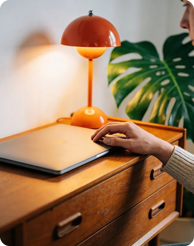Osoba pracująca na laptopie przy biurku z lampą