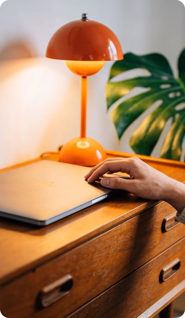 Dłonie na laptopie przy biurku z pomarańczową lampą
