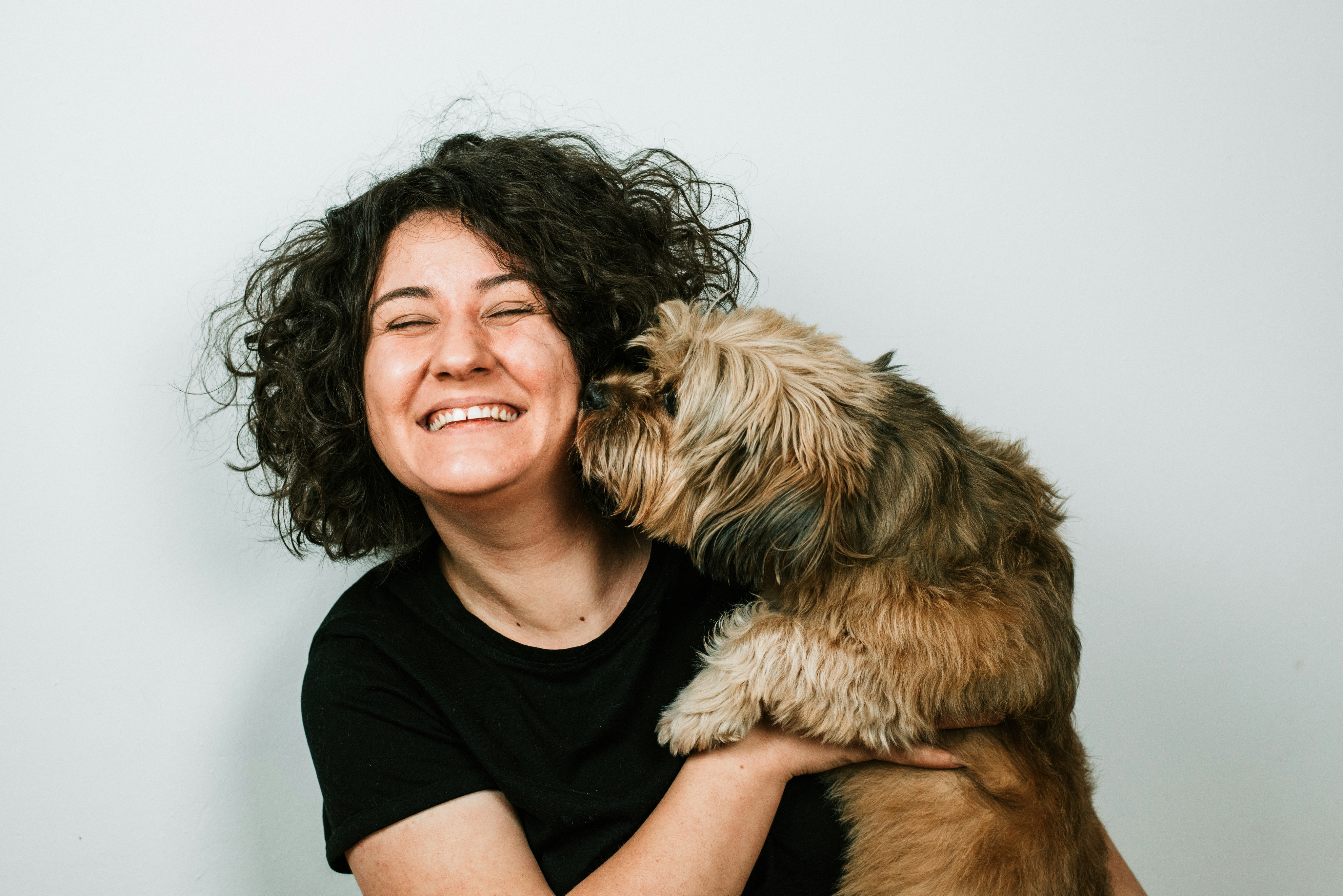 Woman laughing while her dog nuzzles her cheek