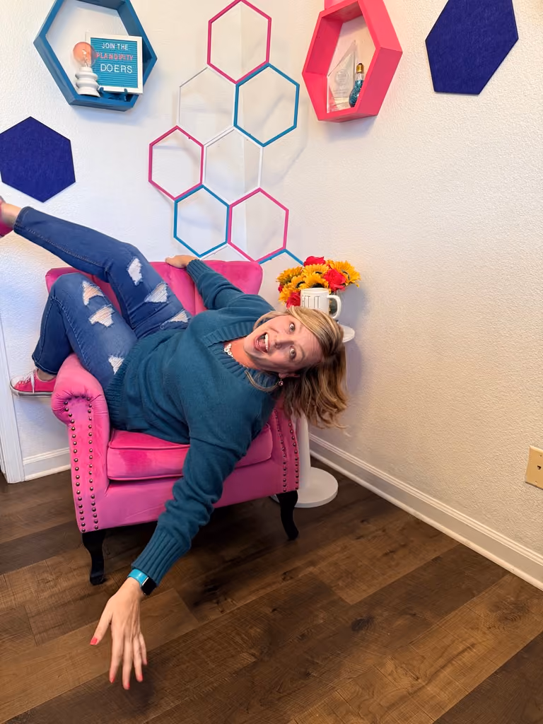 Samantha Markey lounging on pink chair with flowers, Plandipity Doers workspace with hexagonal shelves