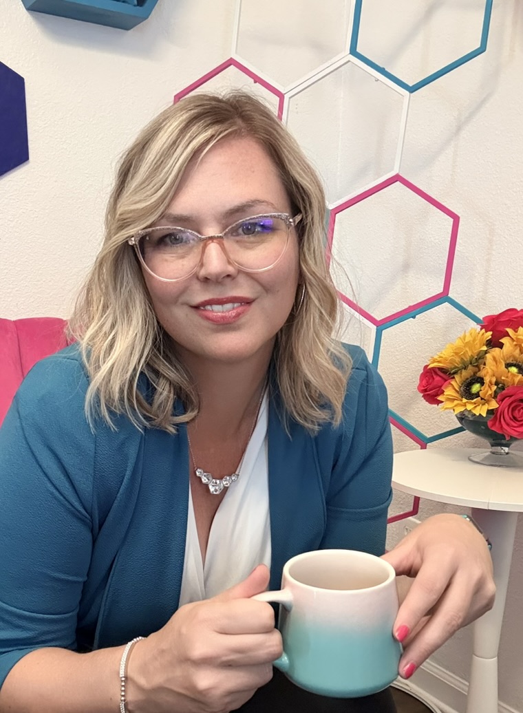 Samantha Markey with glasses holding coffee mug in Plandipity Doers office environment.