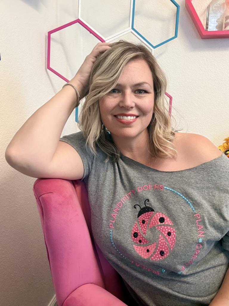 Smiling woman wearing Plandipity Doers ladybug t-shirt with colorful geometric shapes