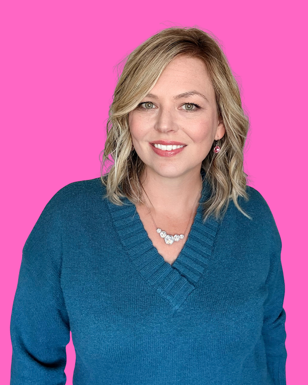 Samantha Markey smiling portrait against vibrant pink background wearing teal sweater