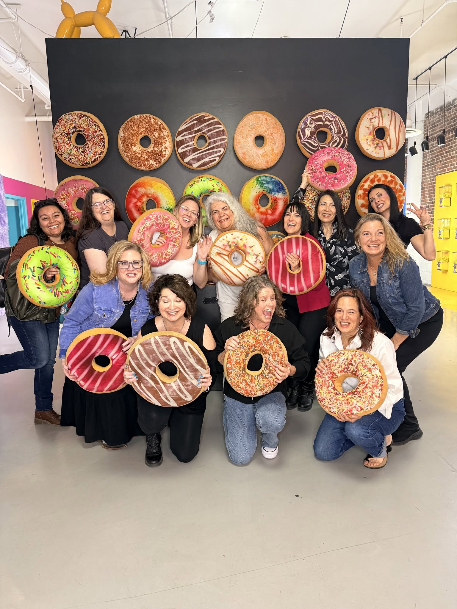 Samantha Markey and team pose with colorful giant donut props at gallery