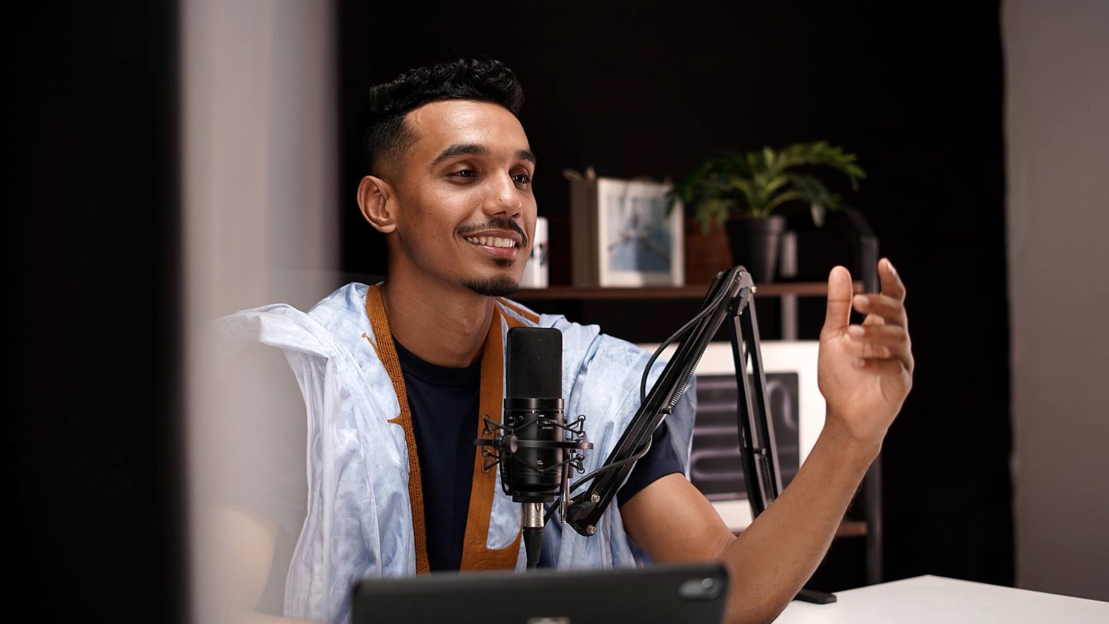 مقدم بودكاست يتحدث أمام ميكروفون في استوديو منزلي