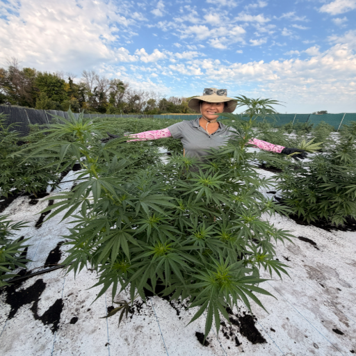 Kathy standing in the rows with arms outstretched across the canopy