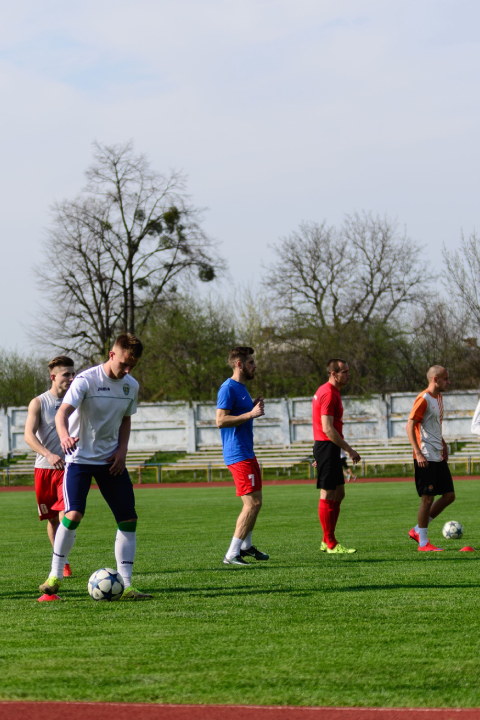Soccer players participating in a training drill with soccer balls on an outdoor field.