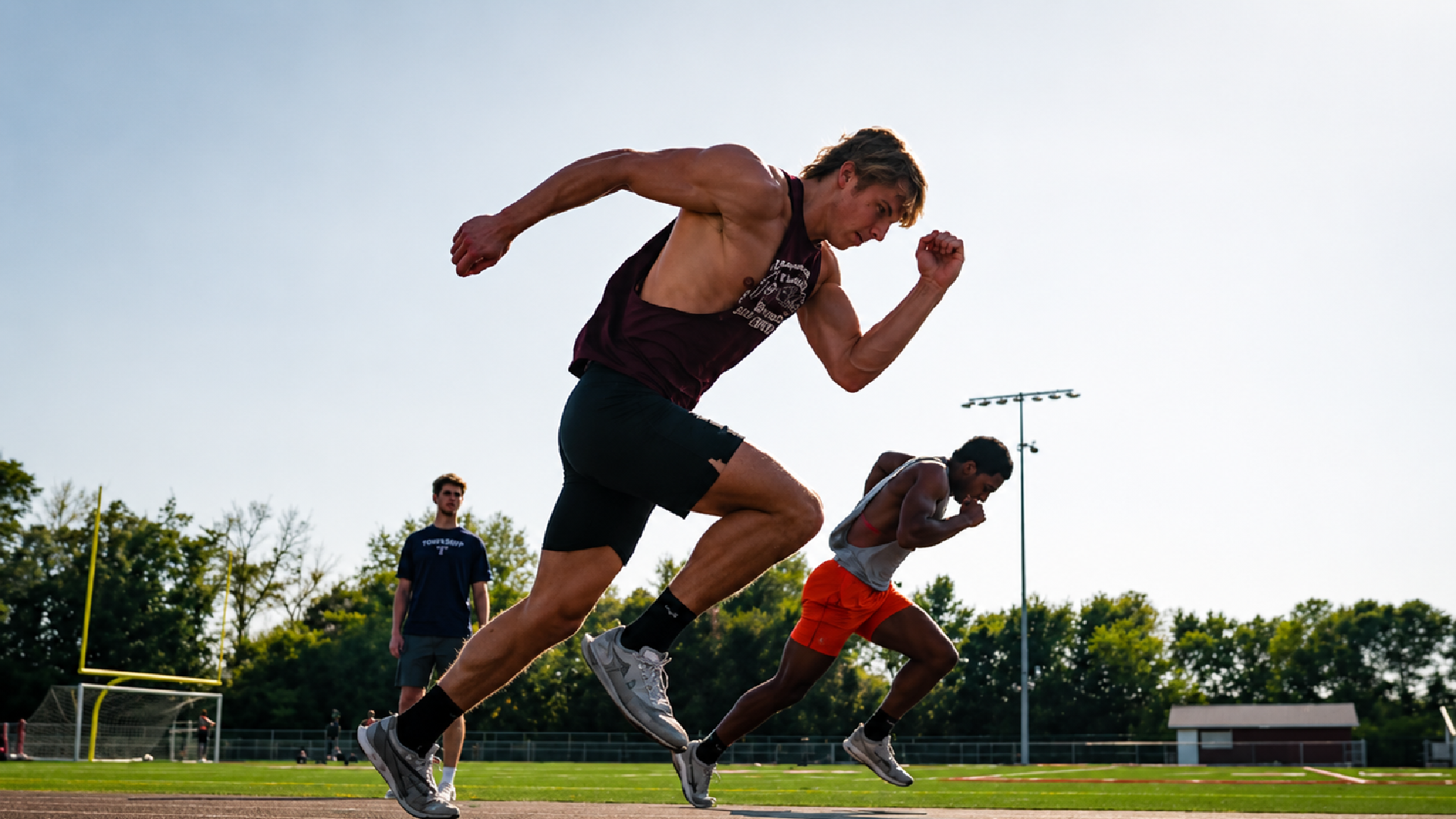 Two athletes sprint on an outdoor track during performance training in Edina, Minnesota.