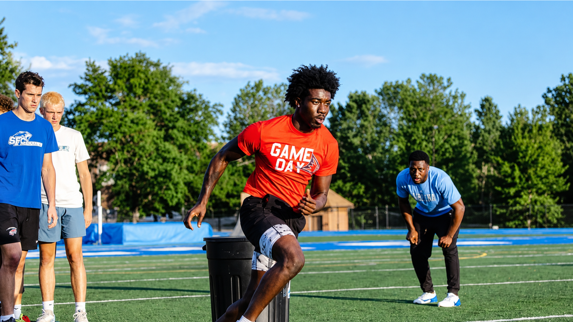 Athlete performing a speed and agility drill on a football field while other athletes watch.