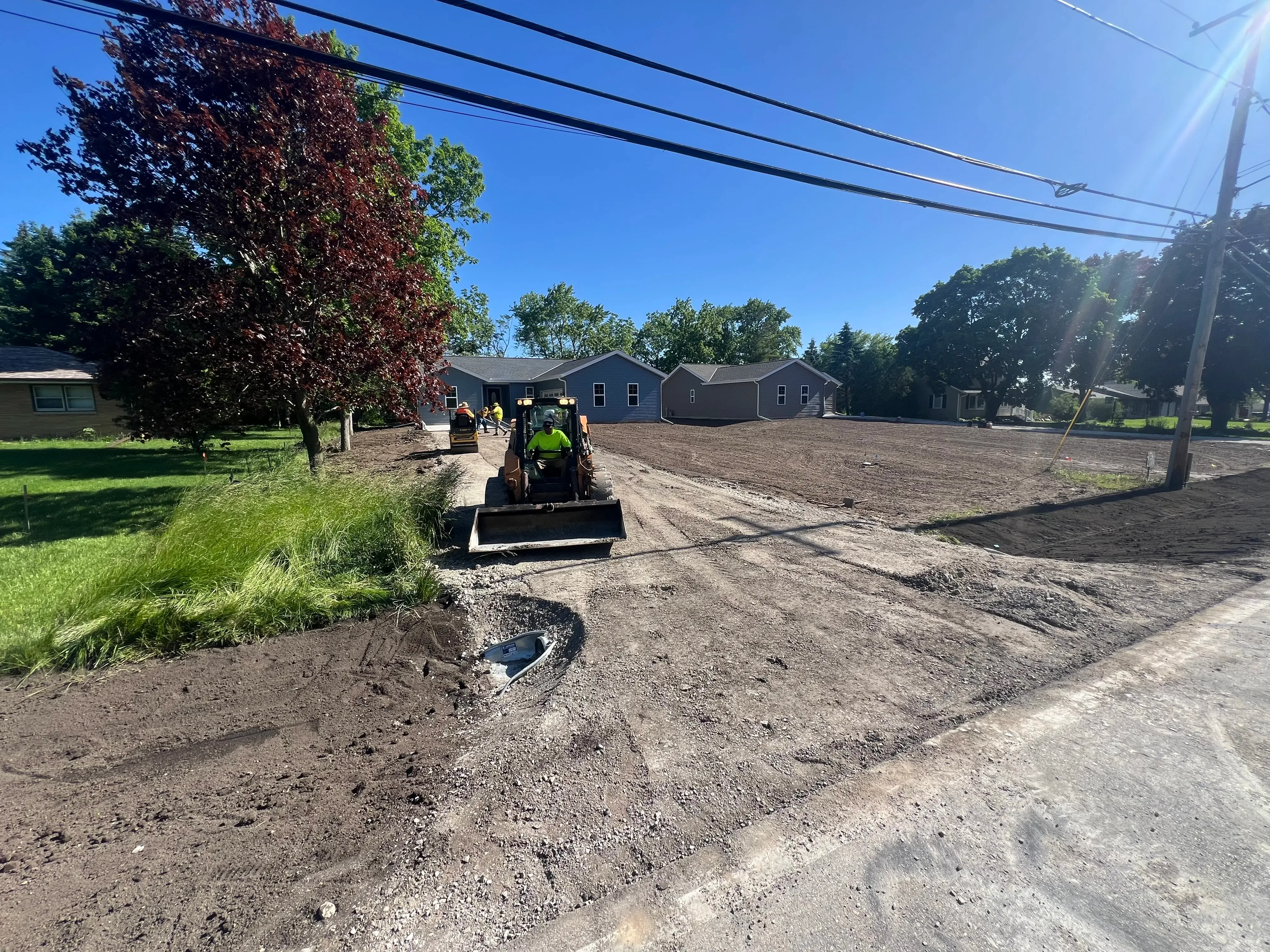 Skid steer grading the gravel base before asphalt is laid