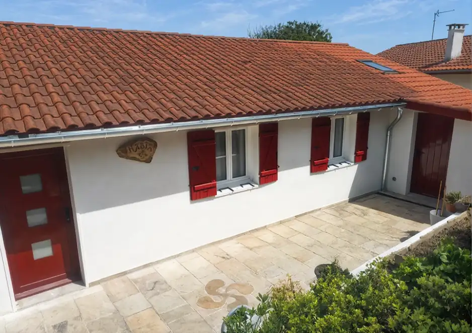 Maison basque à volets rouges dont la toiture en tuiles est entretenue, à Bidart
