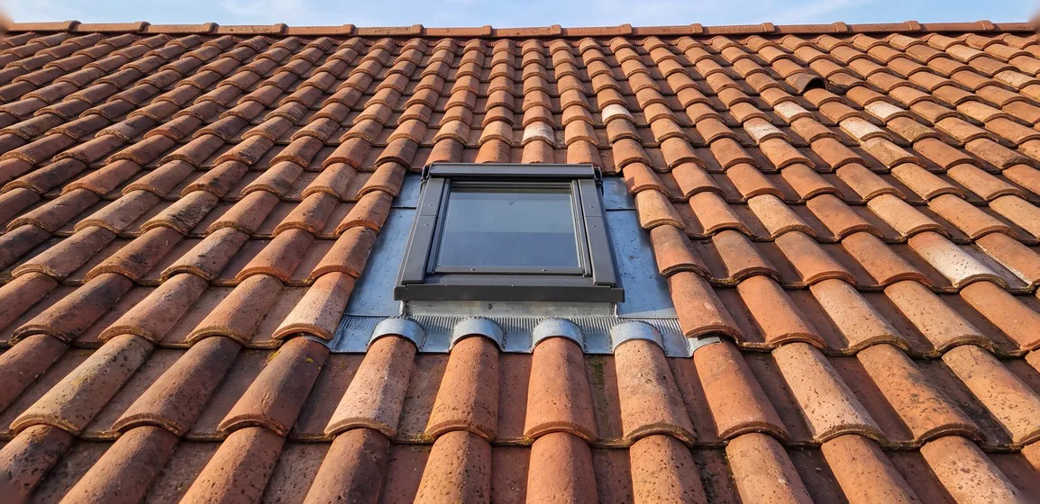Fenêtre de toit Velux fermée sur une toiture en tuiles, raccord zinc étanche vu de face