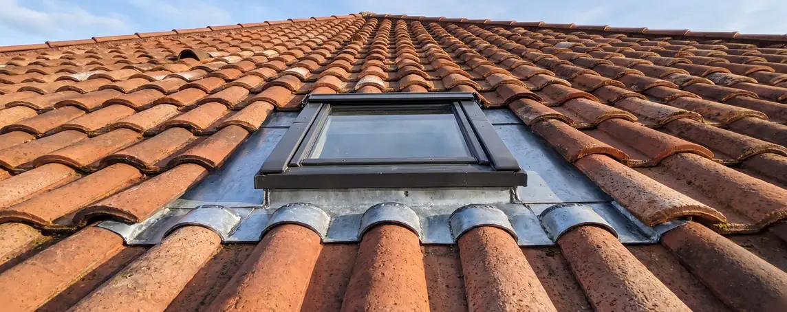 Velux neuf posé dans une toiture en tuiles, entourage zinc vu en contre-plongée