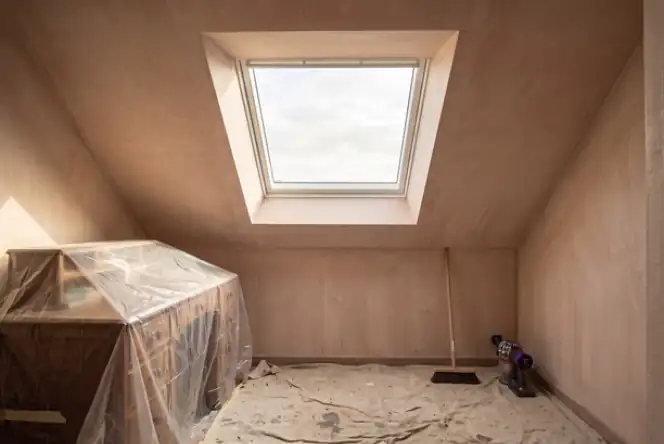 Combles protégés et sol bâché sous une fenêtre de toit, chantier de pose de Velux laissé propre