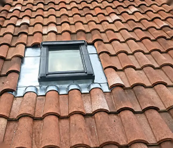 Entourage en zinc d'une fenêtre de toit sur une couverture en tuiles, rénovation de toiture à Bayonne