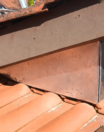Solin en zinc repris au pied d'un mur sur une couverture en tuiles, rénovation de toiture à Bayonne