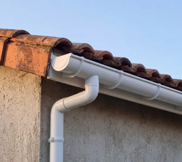 Gouttière PVC blanche et sa descente sur un mur crépi, option économique d'une pose de gouttière à Bayonne
