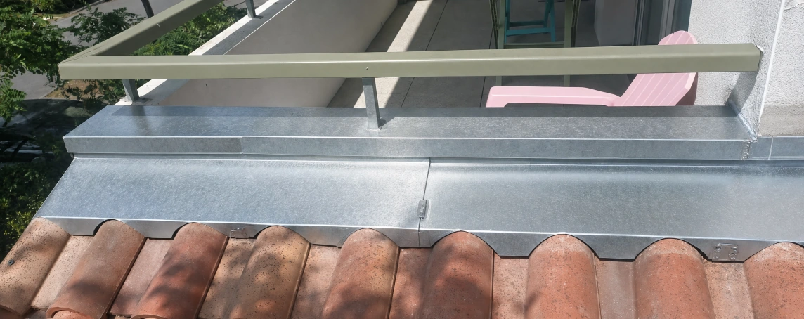 Bavette et rive zinc au raccord d'une terrasse et d'une couverture en tuiles à Bayonne