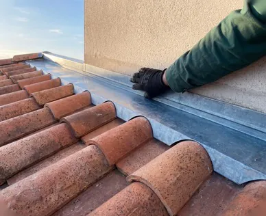 Pose à la main d'une bavette zinc contre un mur sur une toiture à Bayonne