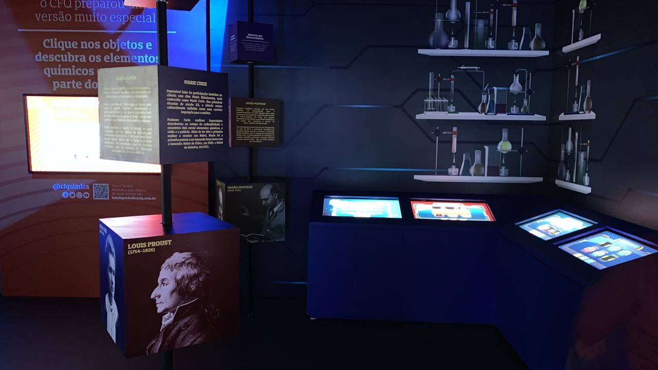 Inside Espaço Q: backlit shelves of laboratory glassware, printed panels and touchscreen totems